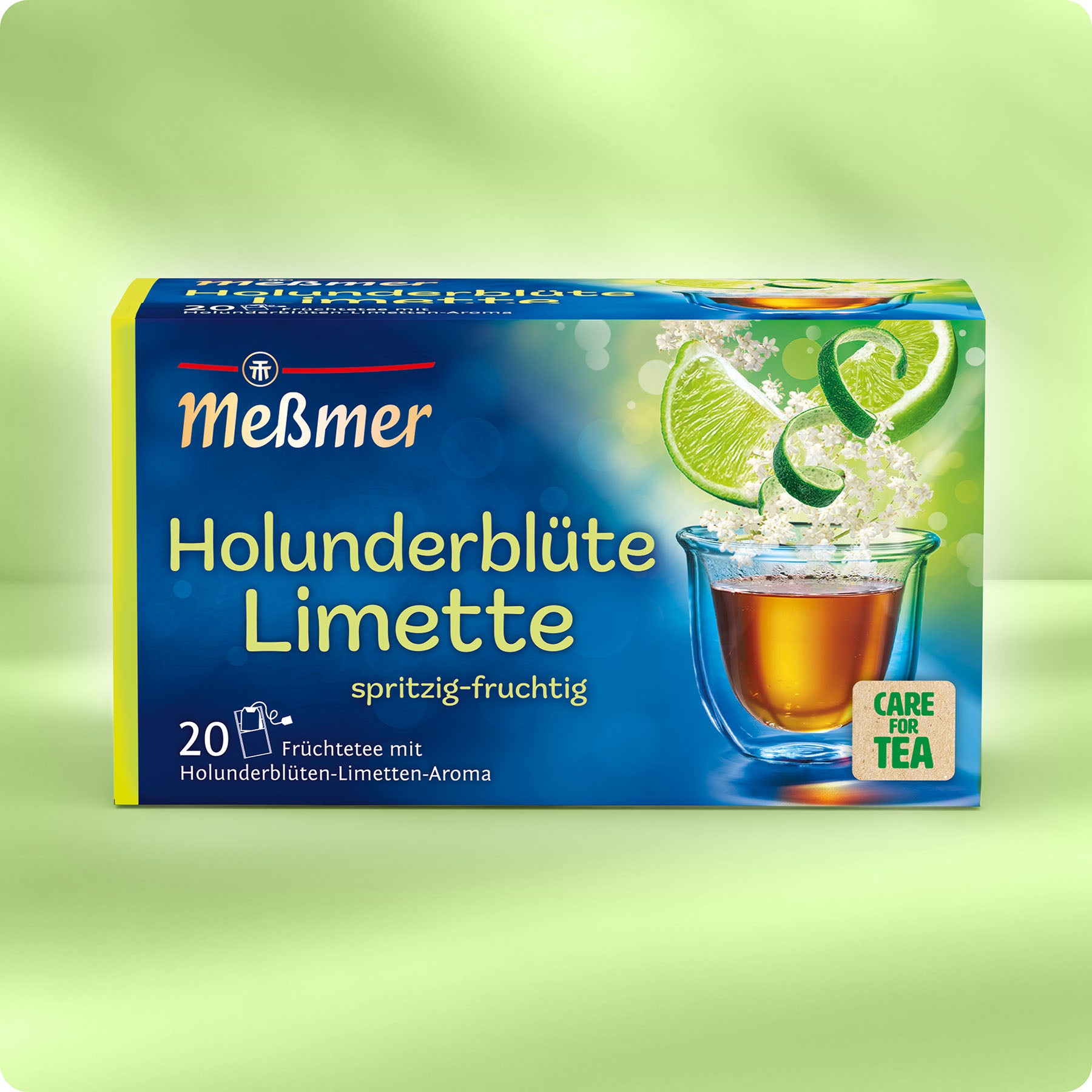 Holunderblüte Limette TEST Teepackung mit spritzig-fruchtigem Aroma, zeigt frische Limettenscheiben und Holunderblüten auf grünem Hintergrund.
