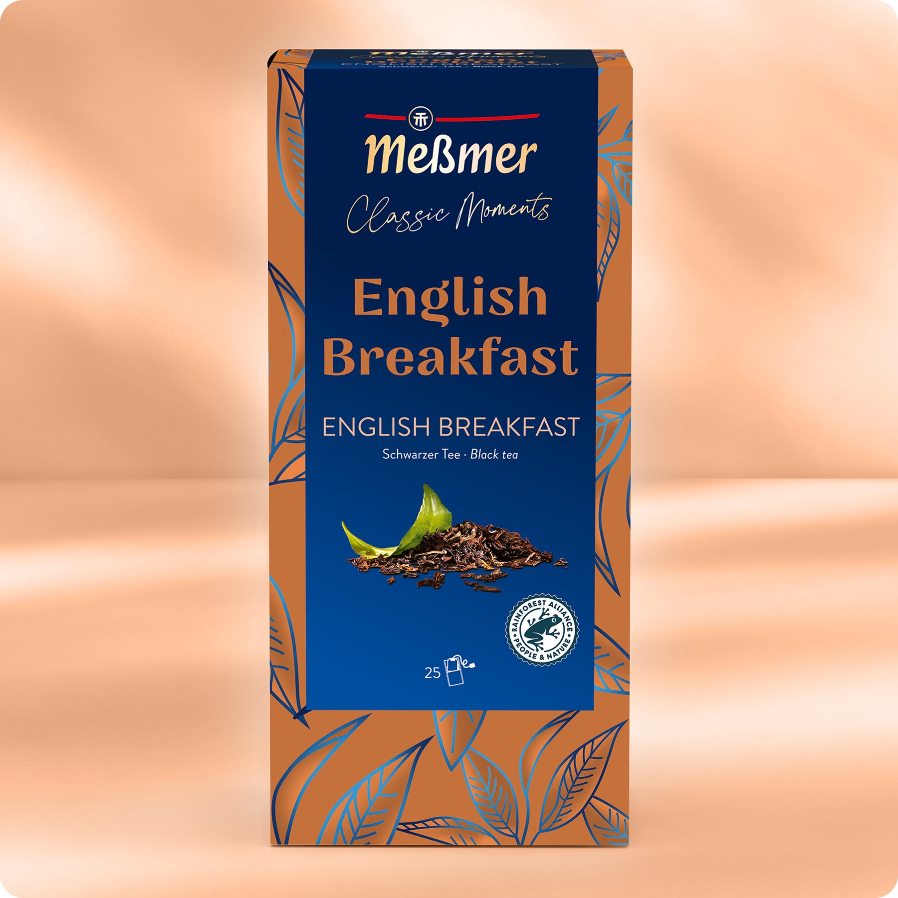 Eine Schachtel Meßmer DE English Breakfast mit blauem und kupferfarbenem Blattdesign mit dem Fairtrade-Logo und den Schwerpunkten Assam- und Ceylon-Tees. Jede Schachtel enthält 25 Teebeutel.