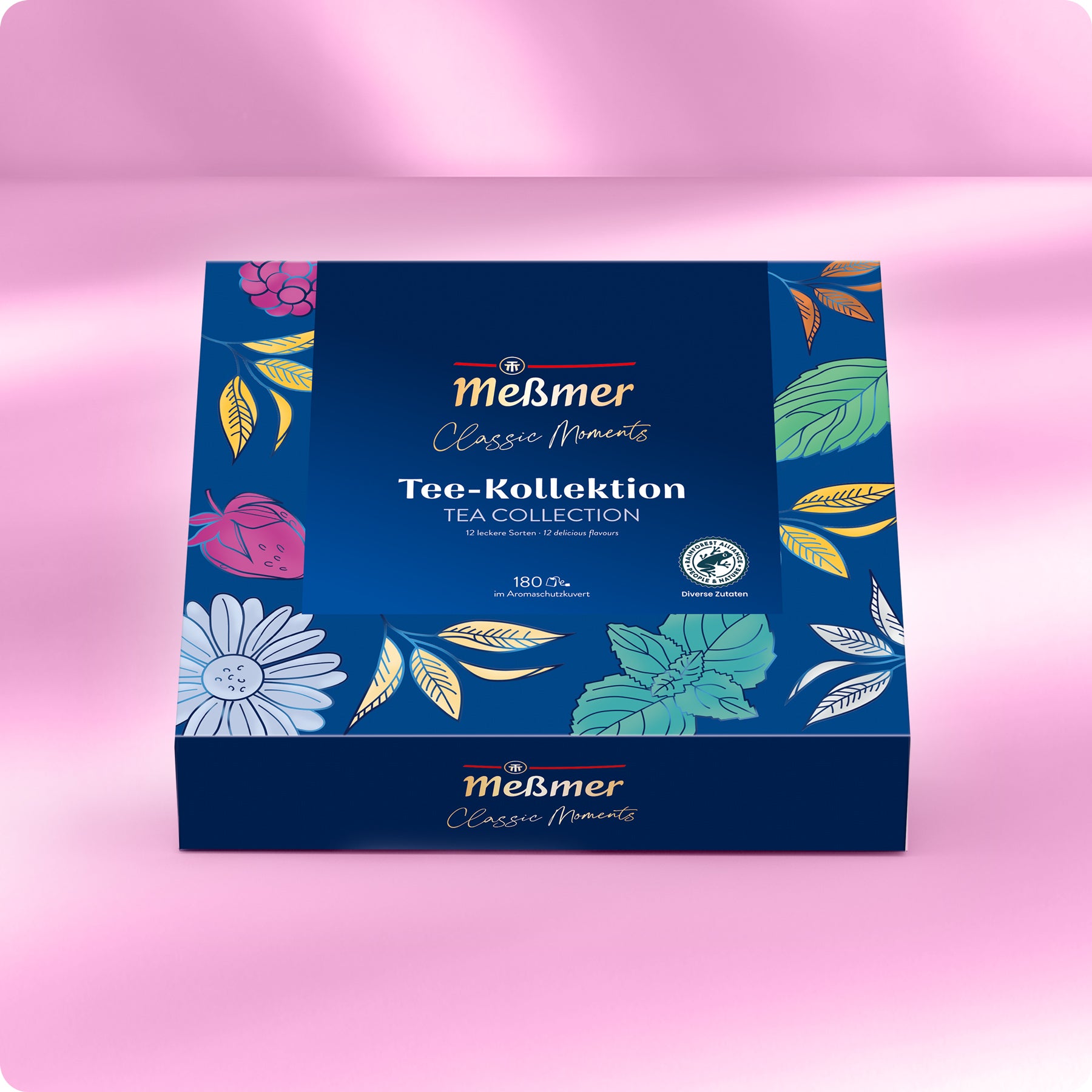 Eine blaue Meßmer DE Tea Collection Box mit lebhaften Blumen- und Blattmotiven ist auf einer rosa Oberfläche abgebildet. Die Verpackung in deutscher und englischer Sprache weist auf 180 Teebeutel im Inneren hin.