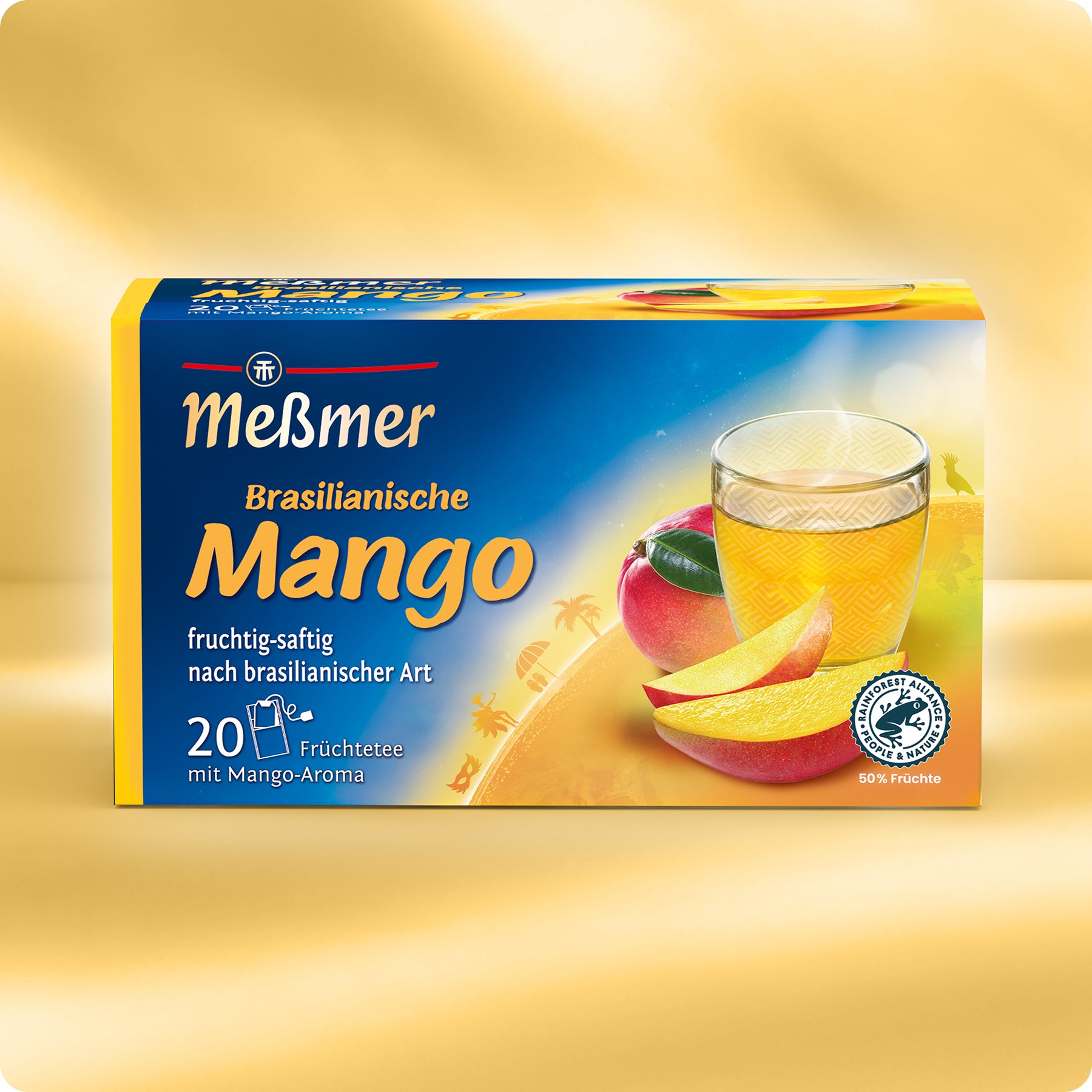 Eine Schachtel Meßmer DE Brasilianische Mango, präsentiert mit einem Glas exotischem Tee, frischen Mangoscheiben und einer ganzen Mango auf einem leuchtend gelben Hintergrund. Jede Schachtel enthält 20 Teebeutel.
