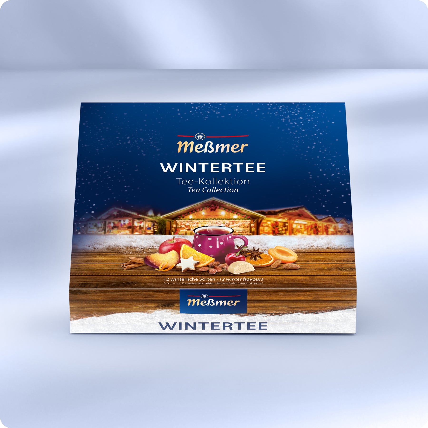 Die Meßmer DE Wintertee Collection Box zeigt eine festliche Verpackung mit einer verschneiten Winterlandschaft, einer Tasse Tee, Früchten, Gewürzen auf Holz und gemütlichen Häusern im Hintergrund.