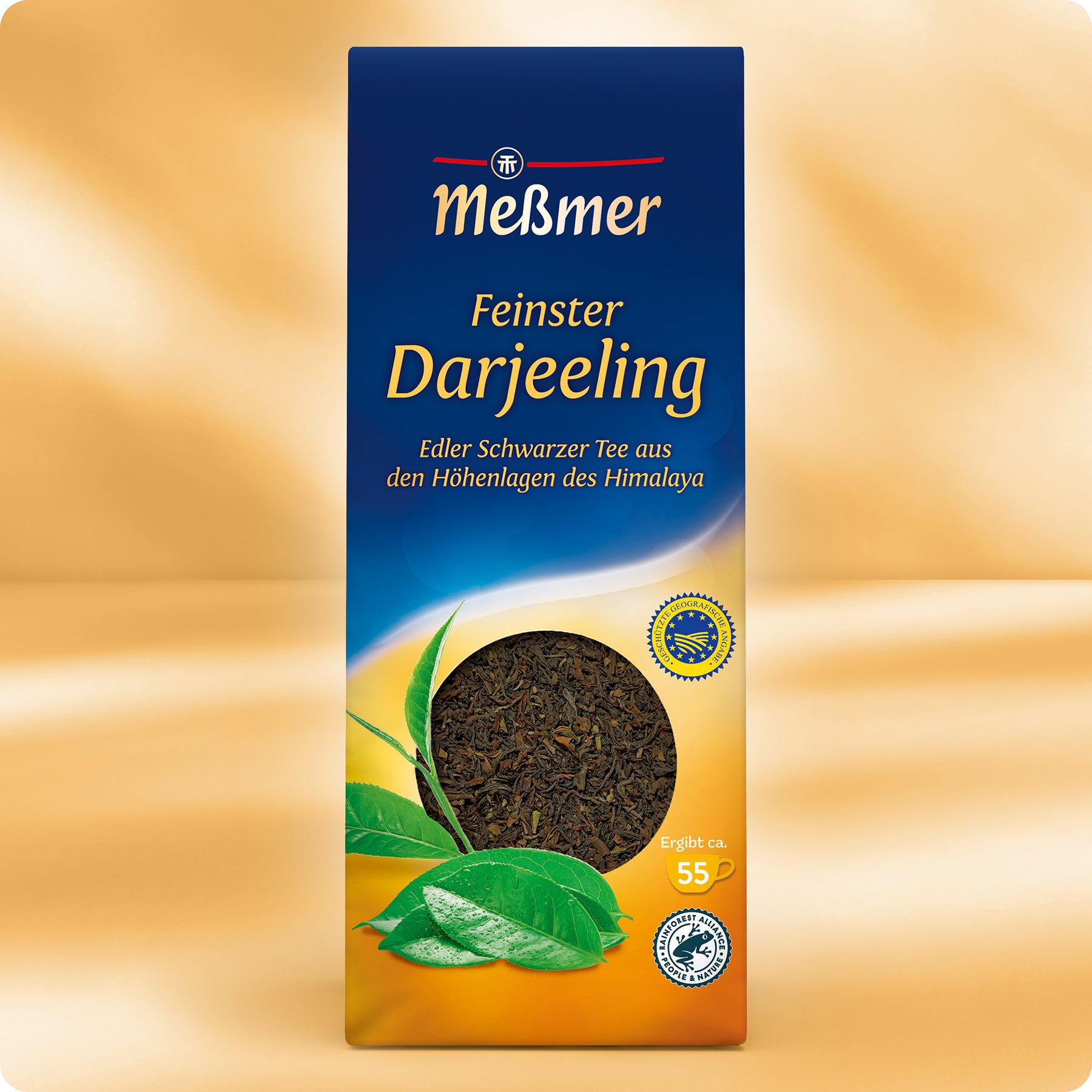 Eine Schachtel Meßmer DE Feinster Darjeeling-Tee, mit einem runden Fenster, das Schwarztee-Blätter zeigt, Illustrationen von grünen Teeblättern auf goldenem Hintergrund, die das einzigartige Hochlandklima betonen.