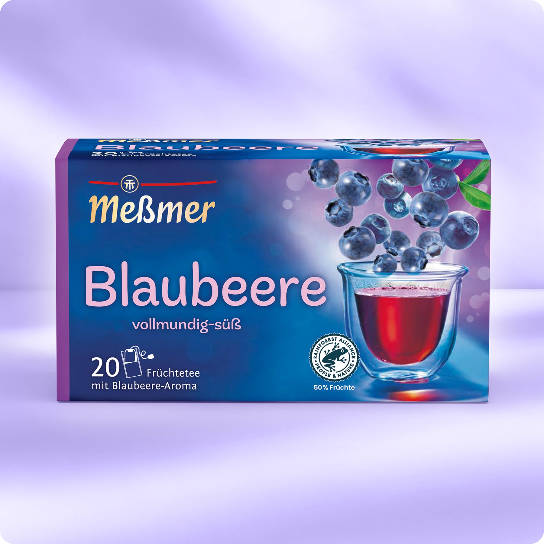 Eine Schachtel Meßmer DE Blaubeere Tee. Die blau-violette Verpackung zeigt Blaubeeren über einem Glas mit rotem Tee. Enthält 20 Teebeutel und Zertifizierungslogos.