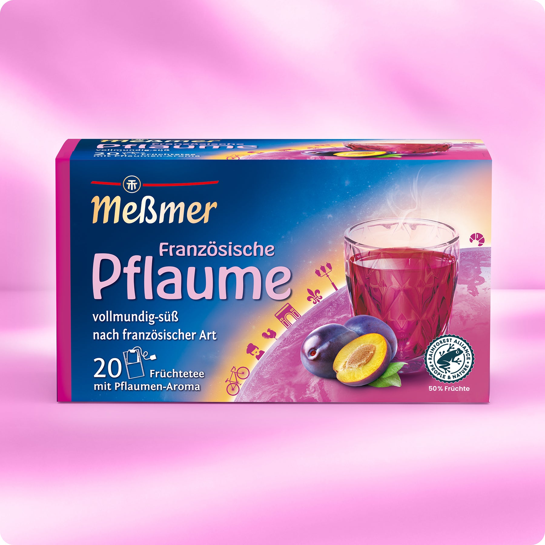 Eine Schachtel Meßmer DE Französische Pflaume Tee ist auf einem rosafarbenen Hintergrund abgebildet. Die Verpackung zeigt ein Glas mit rotem Tee, reife Pflaumen und französische Wahrzeichen wie den Eiffelturm.