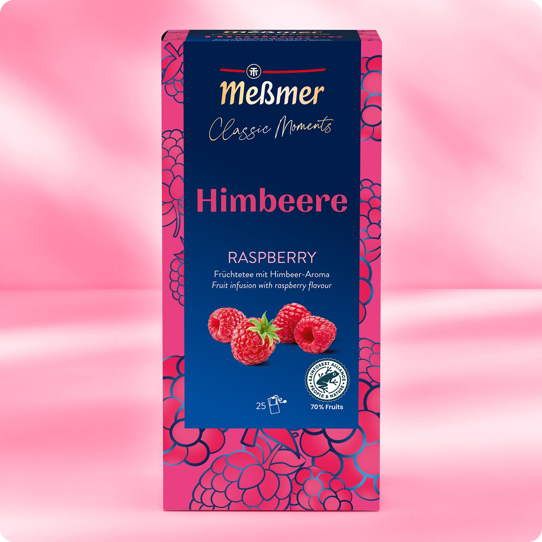Eine Schachtel Meßmer DE Himbeere Tee ist mit Himbeermotiven, mehreren Himbeeren in der Mitte und einer rosa-blauen Verpackung versehen. Der Text ist auf Deutsch und Englisch und hebt den "beerigen Geschmack" dieses Teeklassikers hervor.