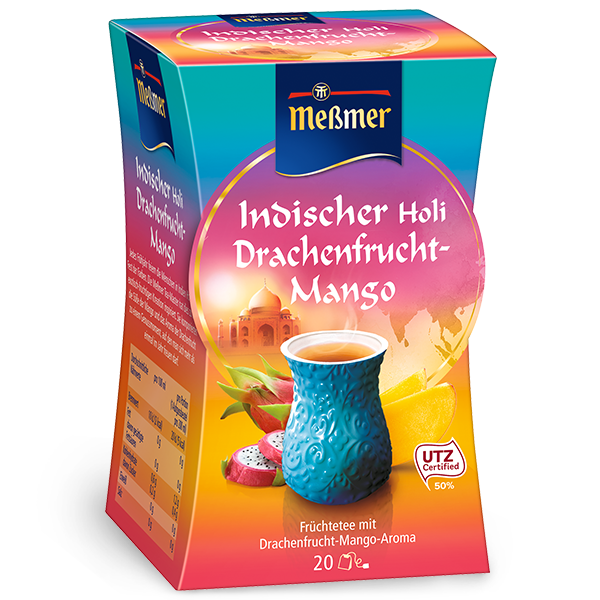 Bunte Verpackung mit einem blauen Teebecher, Früchten und Schriftzug Indischer Holi Drachenfrucht-Mango, Produktname Ausgleich sichtbar auf Vorderseite.