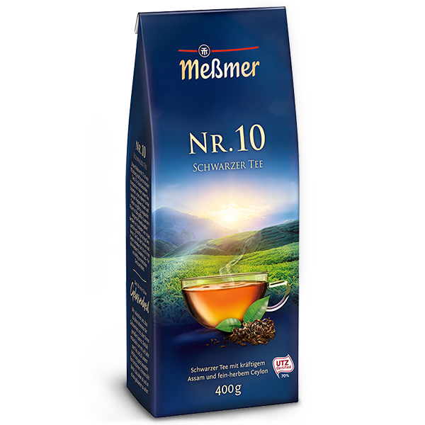 Verpackung vom Old England schwarzer Tee mit aromatischem Assam und Ceylon, 400g, vor einem Sonnenaufgang über grünen Teefeldern.